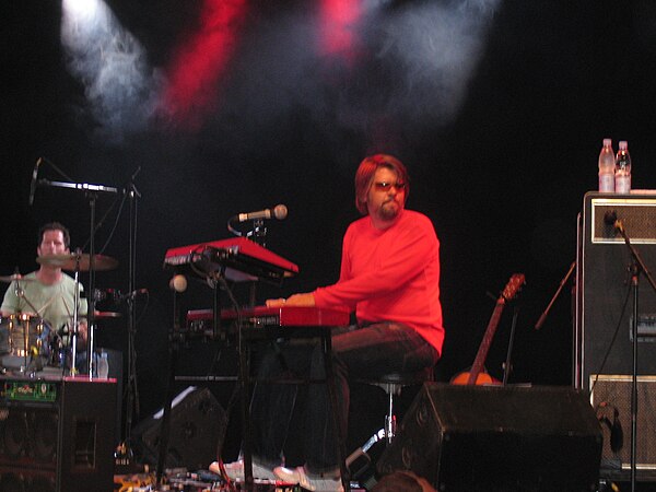 A keyboardist playing a live show with a big Leslie cabinet (visible to his right).